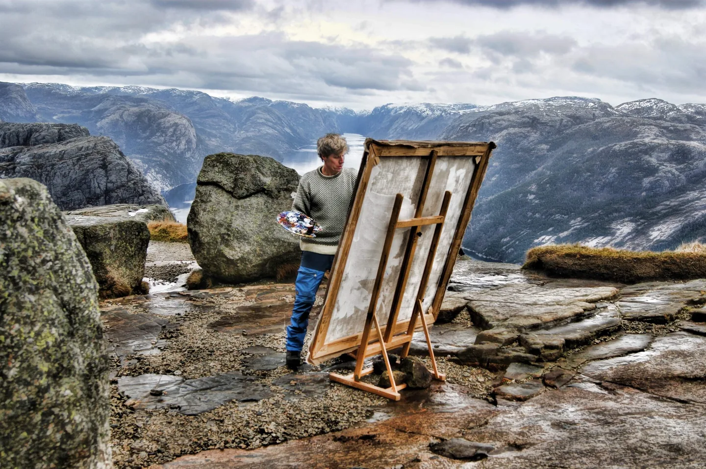 A portrait of the artist Stian Heimlund Skjæveland painting at the Pulpit Rock in Norway.